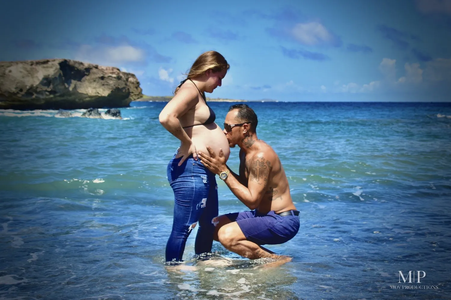 Pregnant woman with her partner in the sea during a maternity photoshoot in Aruba